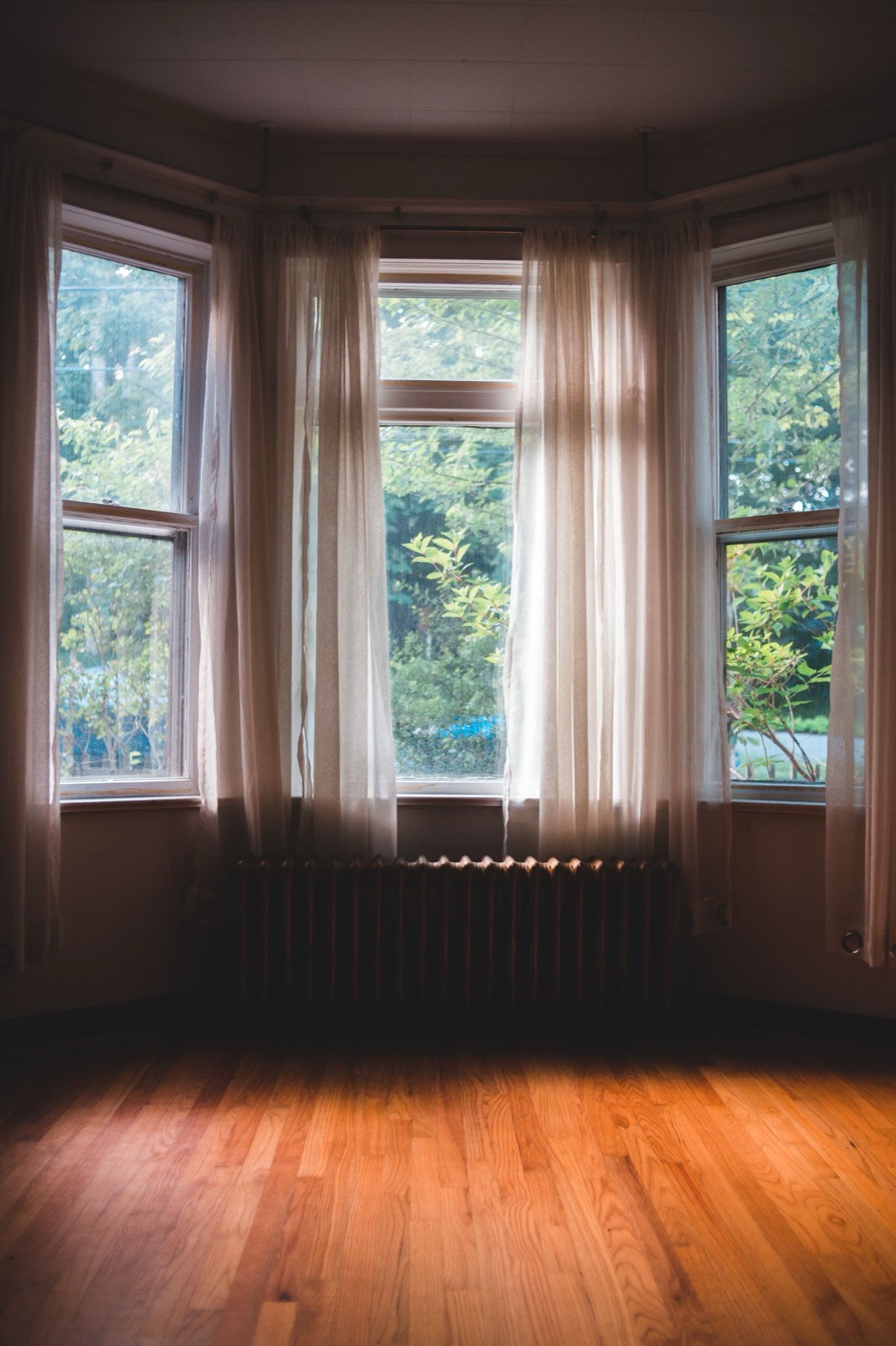 Living room bay window dressed with curtains following the angle of the wall