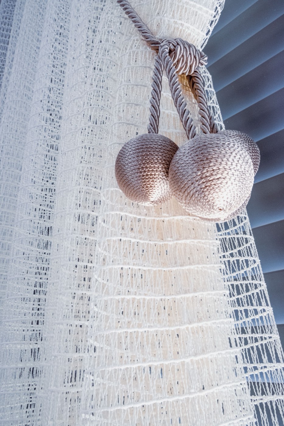 Fabric tieback gathering a sheer curtain panel against the window frame