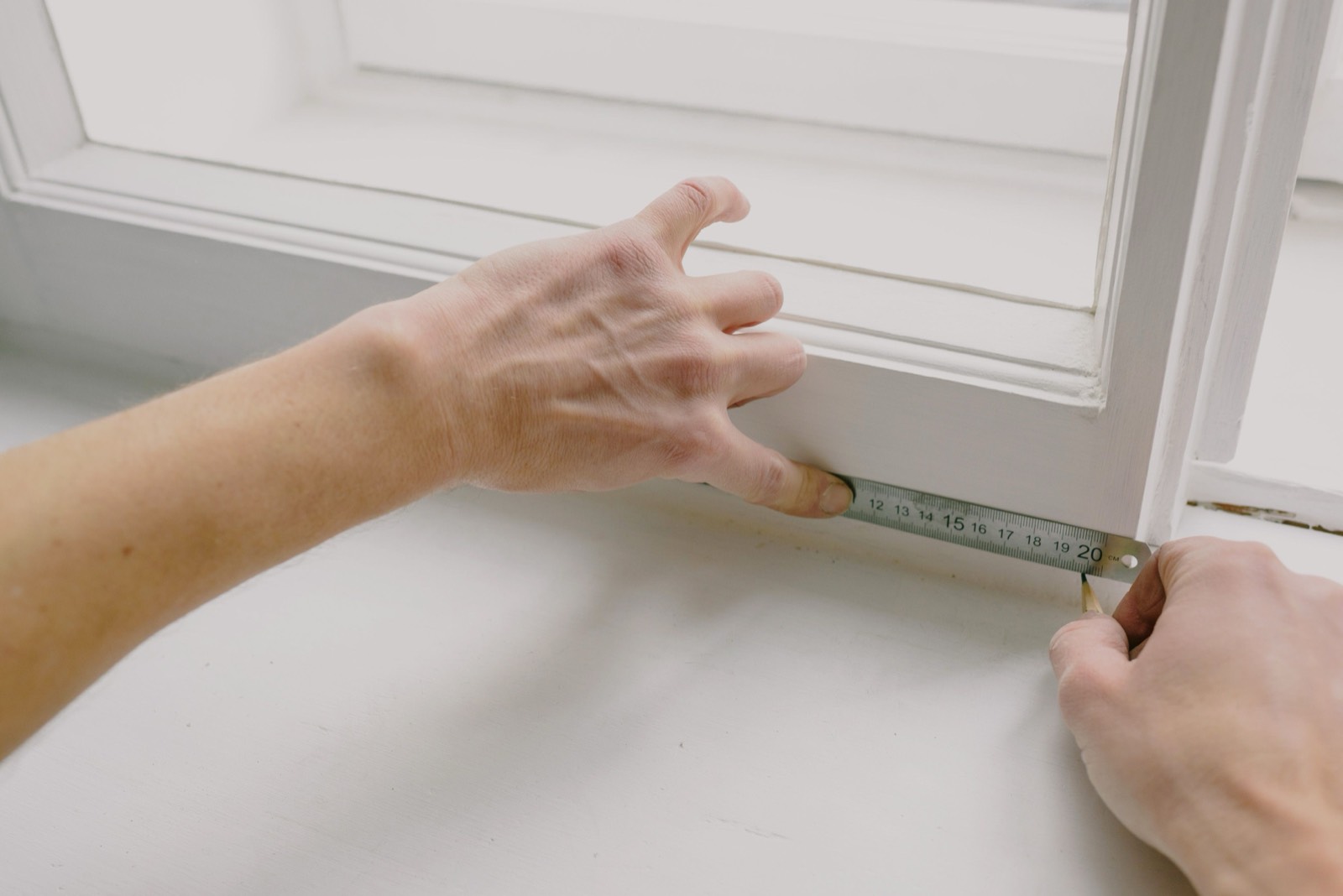Ausmessen eines Fensters mit einem Maßband vor der Bestellung von Gardinen oder Rollos